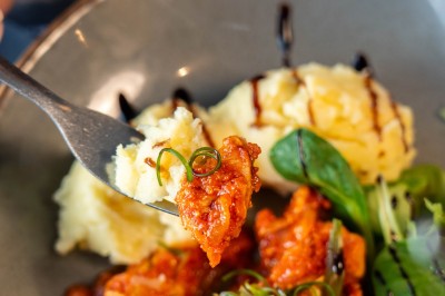 Dessert tiramisu dans une verrine, décoré d'une tranche d'orange séchée, avec une main tenant une cuillère.