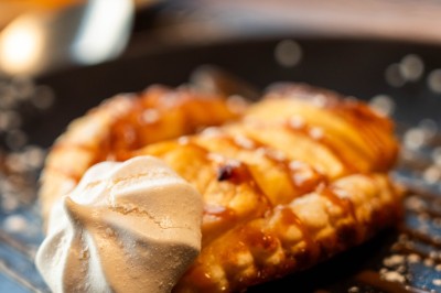Dessert tiramisu dans une verrine, décoré d'une tranche d'orange séchée, avec une main tenant une cuillère.