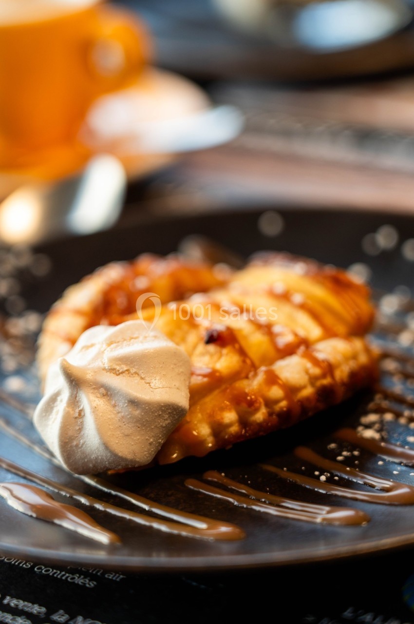 Pâtisserie garnie de caramel et accompagnée d'une meringue, servie sur une assiette noire.