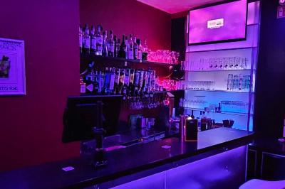 Écran et panneau indiquant ’Karaoké Bar Sablon’ avec un micro, dans une salle éclairée par des lumières violettes.
