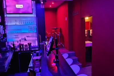 Miniature Location salle Bruxelles (Bruxelles-Capitale) - Karaoke Bar Sablon #3 Scène de karaoké dans un bar avec éclairage rose et rouge, micro illustré sur un panneau mural.