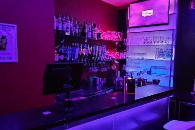 Miniature Location salle Bruxelles (Bruxelles-Capitale) - Karaoke Bar Sablon #4 Scène de karaoké dans un bar avec éclairage rose et rouge, micro illustré sur un panneau mural.