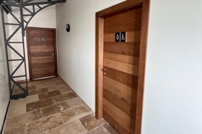 Chambre avec lit double, murs en pierre, poutres apparentes et éclairage doux, décorée de motifs muraux naturels.