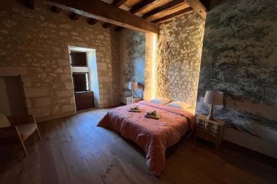 Chambre lumineuse avec un lit double, mur jaune, parquet en bois, escalier et coin détente avec fauteuils pliants.