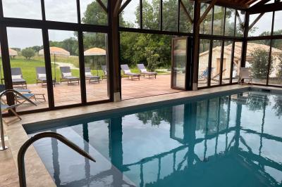 Chambre lumineuse avec un lit double, mur jaune, parquet en bois, escalier et coin détente avec fauteuils pliants.
