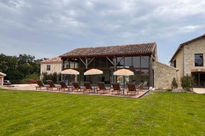 Chambre lumineuse avec un lit double, mur jaune, parquet en bois, escalier et coin détente avec fauteuils pliants.