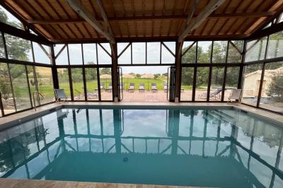 Chambre lumineuse avec un lit double, mur jaune, parquet en bois, escalier et coin détente avec fauteuils pliants.