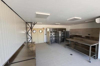 Chambre lumineuse avec un lit double, mur jaune, parquet en bois, escalier et coin détente avec fauteuils pliants.