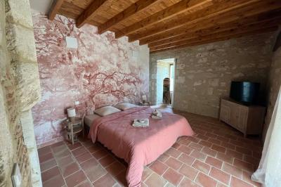 Chambre lumineuse avec un lit double, mur jaune, parquet en bois, escalier et coin détente avec fauteuils pliants.
