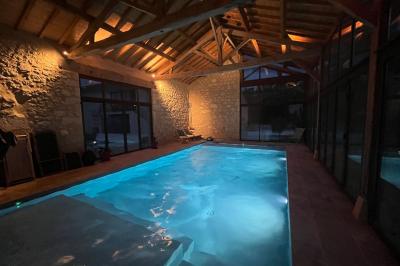 Chambre lumineuse avec un lit double, mur jaune, parquet en bois, escalier et coin détente avec fauteuils pliants.