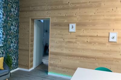 Toilettes modernes avec murs en bois clair, étagère intégrée contenant des produits ménagers dans un panier tressé.