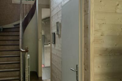 Toilettes modernes avec murs en bois clair, étagère intégrée contenant des produits ménagers dans un panier tressé.