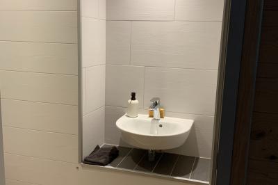 Toilettes modernes avec murs en bois clair, étagère intégrée contenant des produits ménagers dans un panier tressé.