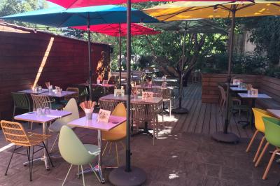 Vue d'un espace lumineux avec des chaises colorées autour d'une table, un comptoir d'accueil et des menus affichés au mur.