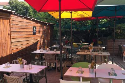 Vue d'un espace lumineux avec des chaises colorées autour d'une table, un comptoir d'accueil et des menus affichés au mur.