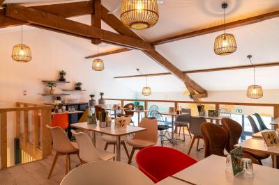 Vue d'un espace lumineux avec des chaises colorées autour d'une table, un comptoir d'accueil et des menus affichés au mur.