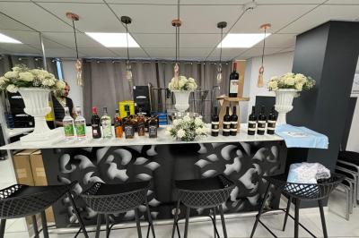 Réfrigérateur en acier inoxydable à double porte dans une pièce aux murs carrelés, avec une porte blanche ouverte.