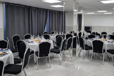 Réfrigérateur en acier inoxydable à double porte dans une pièce aux murs carrelés, avec une porte blanche ouverte.