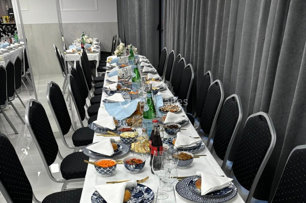 Table dressée pour un repas, avec vaisselle bleue, serviettes blanches, plats variés et boissons disposés.