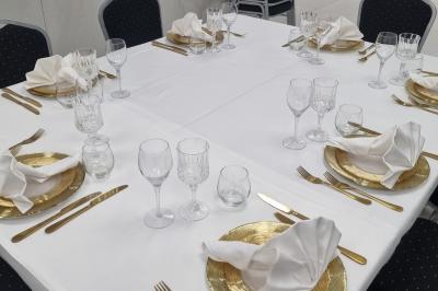 Réfrigérateur en acier inoxydable à double porte dans une pièce aux murs carrelés, avec une porte blanche ouverte.