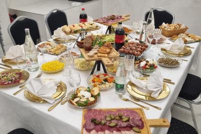 Réfrigérateur en acier inoxydable à double porte dans une pièce aux murs carrelés, avec une porte blanche ouverte.