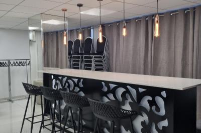 Réfrigérateur en acier inoxydable à double porte dans une pièce aux murs carrelés, avec une porte blanche ouverte.