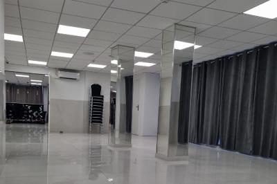 Réfrigérateur en acier inoxydable à double porte dans une pièce aux murs carrelés, avec une porte blanche ouverte.