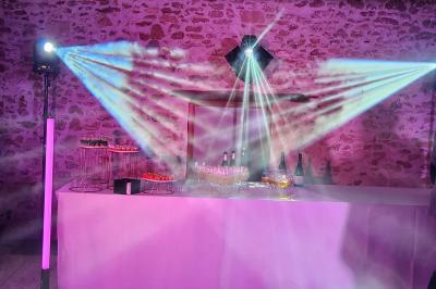 Des invités dansent autour de la mariée tenant des rubans colorés sous des guirlandes lumineuses dans une salle festive.