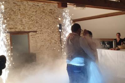 Des invités dansent autour de la mariée tenant des rubans colorés sous des guirlandes lumineuses dans une salle festive.