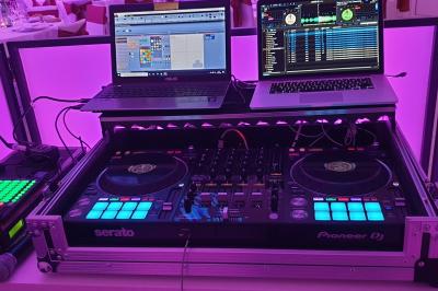 Des invités dansent autour de la mariée tenant des rubans colorés sous des guirlandes lumineuses dans une salle festive.