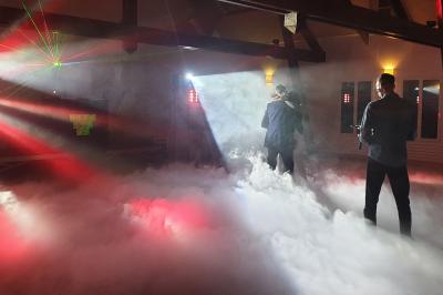 Des invités dansent autour de la mariée tenant des rubans colorés sous des guirlandes lumineuses dans une salle festive.