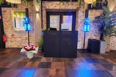 Des invités dansent autour de la mariée tenant des rubans colorés sous des guirlandes lumineuses dans une salle festive.