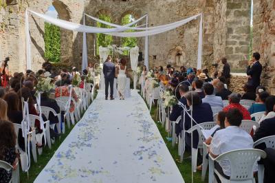 Des invités dansent autour de la mariée tenant des rubans colorés sous des guirlandes lumineuses dans une salle festive.