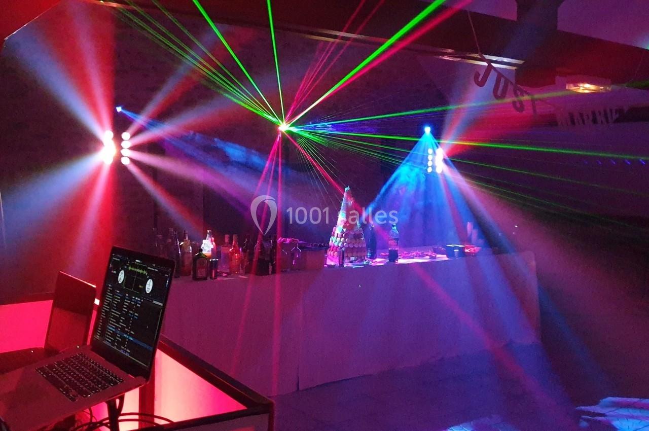 Jeu de lumières colorées et lasers éclairant une salle avec une table de mixage et un ordinateur portable.