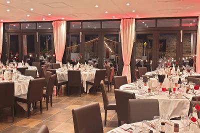 Salle de réception élégante avec tables rondes dressées, nappes blanches et décorations florales rouges.