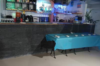 Salle décorée pour une fête avec une longue table dressée, bougies, confettis et ballons dorés.