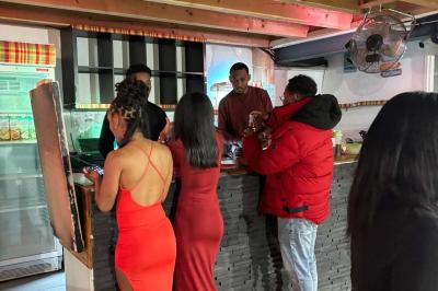 Salle décorée pour une fête avec une longue table dressée, bougies, confettis et ballons dorés.