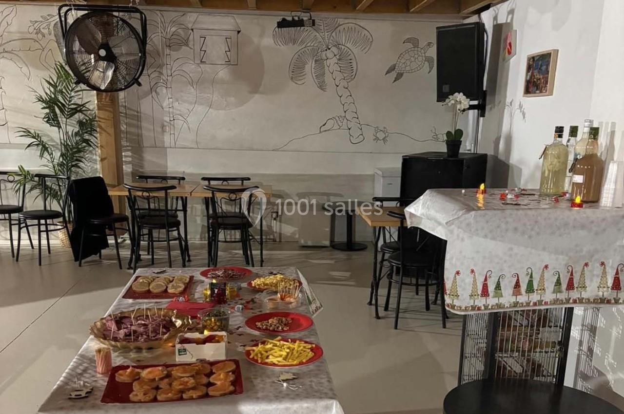 Salle décorée avec des tables et un buffet contenant des amuse-bouches, des boissons et des décorations festives.