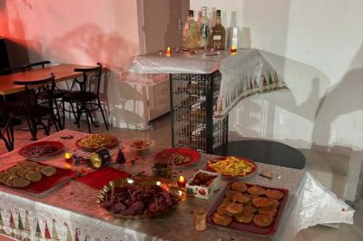 Salle décorée pour une fête avec une longue table dressée, bougies, confettis et ballons dorés.
