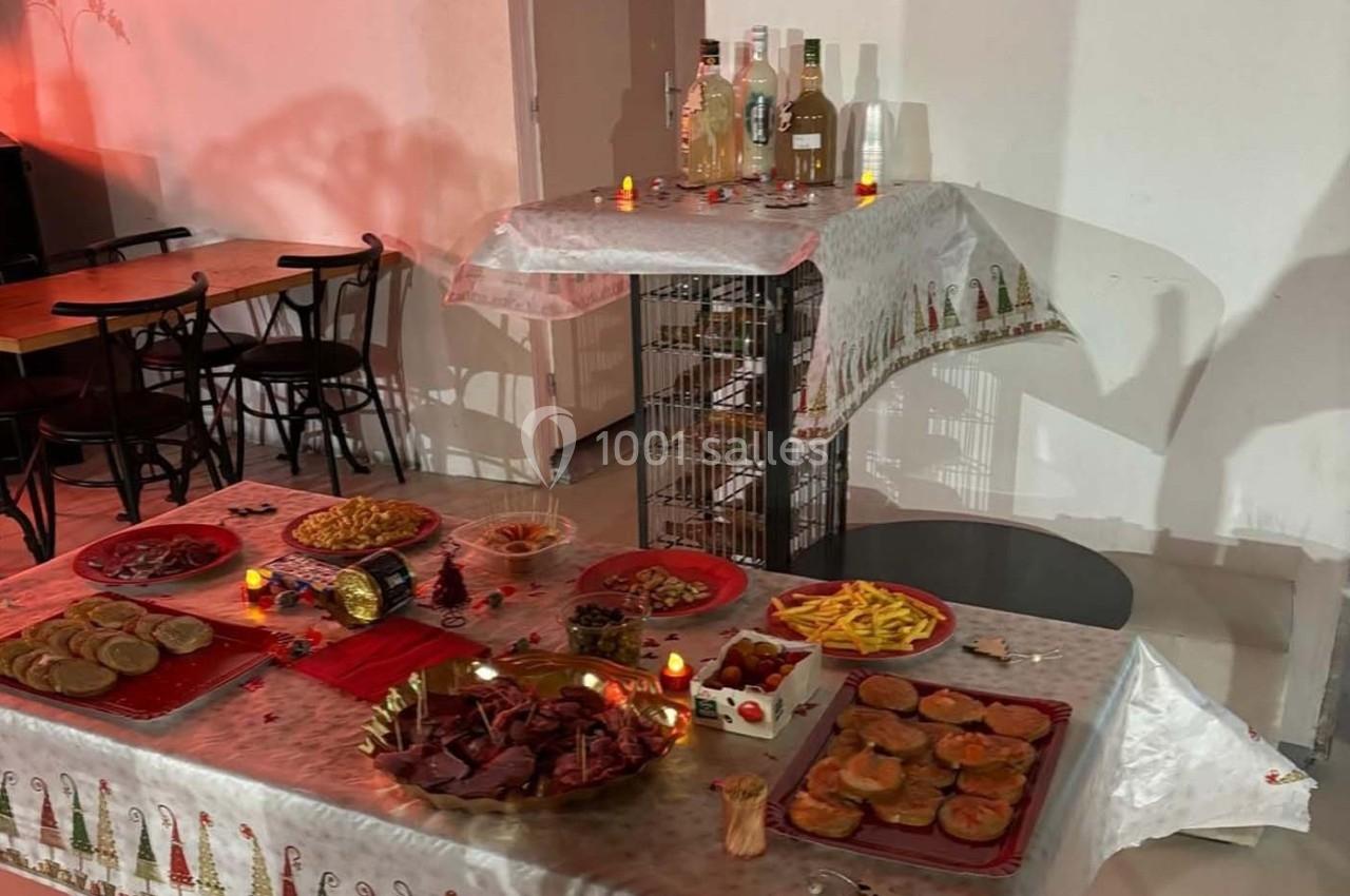 Table garnie de plats variés, apéritifs et boissons, décorée pour une ambiance festive avec bougies et nappes à motifs.