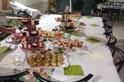 Salle décorée pour une fête avec une longue table dressée, bougies, confettis et ballons dorés.