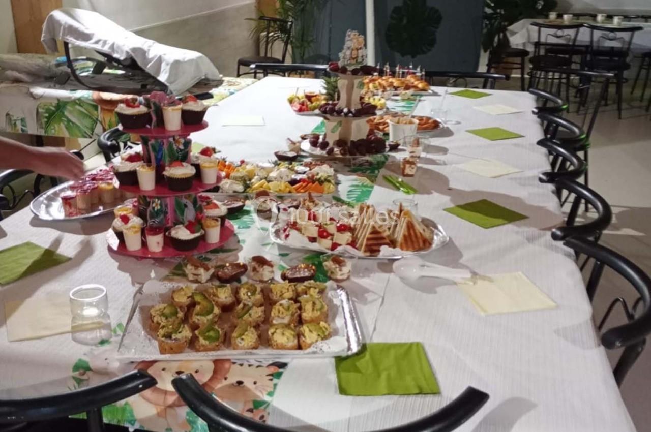 Table dressée avec un buffet varié comprenant des amuse-bouches, desserts et gâteaux, dans un cadre convivial.