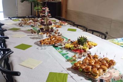 Salle décorée pour une fête avec une longue table dressée, bougies, confettis et ballons dorés.