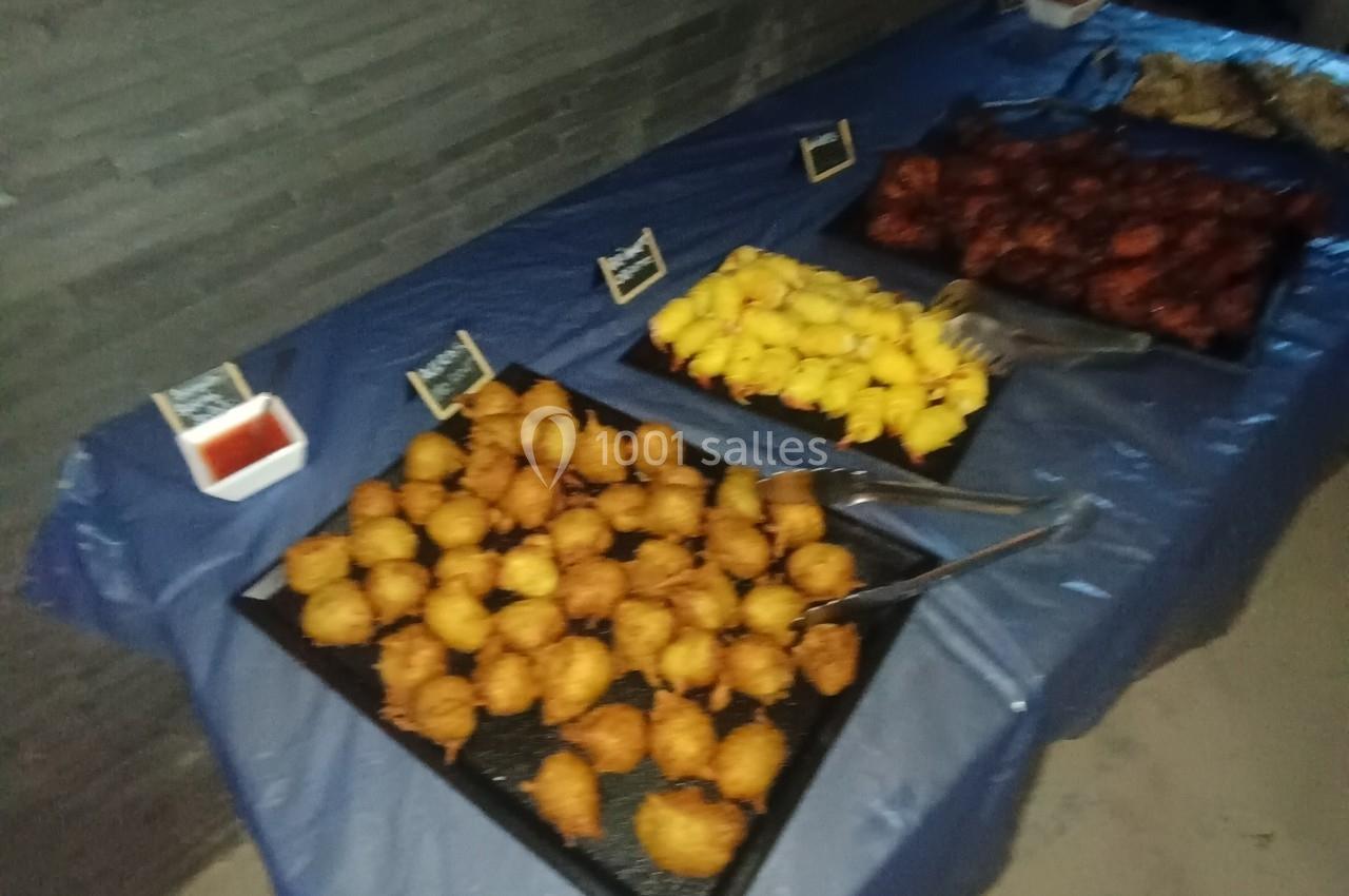 Plateau de beignets variés disposés sur une table recouverte d'une nappe bleue, avec des étiquettes descriptives.