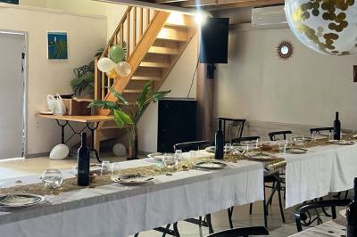 Salle décorée pour une fête avec une longue table dressée, bougies, confettis et ballons dorés.