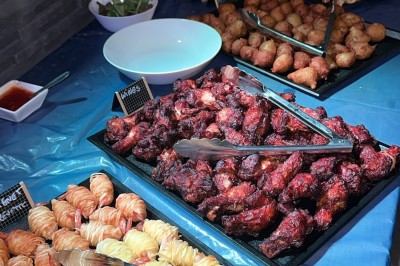 Salle décorée pour une fête avec une longue table dressée, bougies, confettis et ballons dorés.