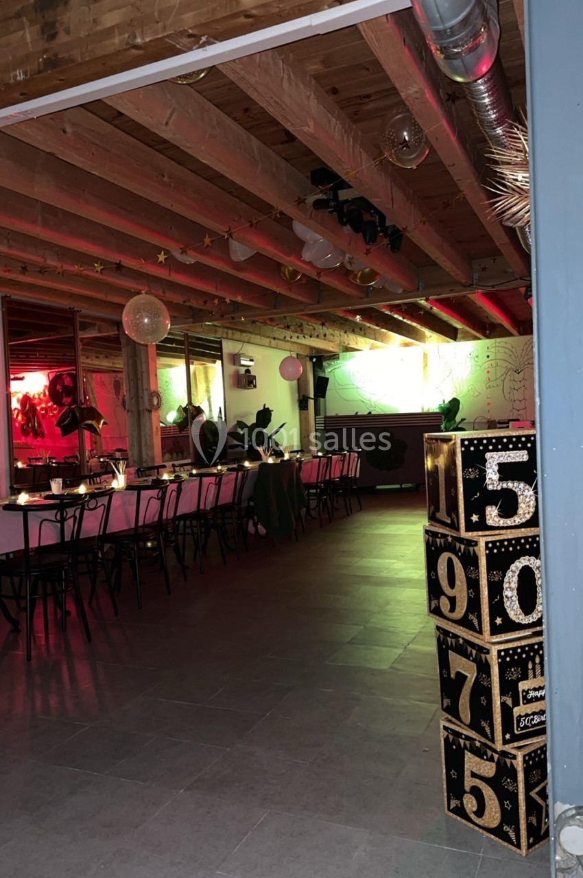 Salle décorée avec des tables alignées, éclairage coloré et cubes numérotés empilés au premier plan.