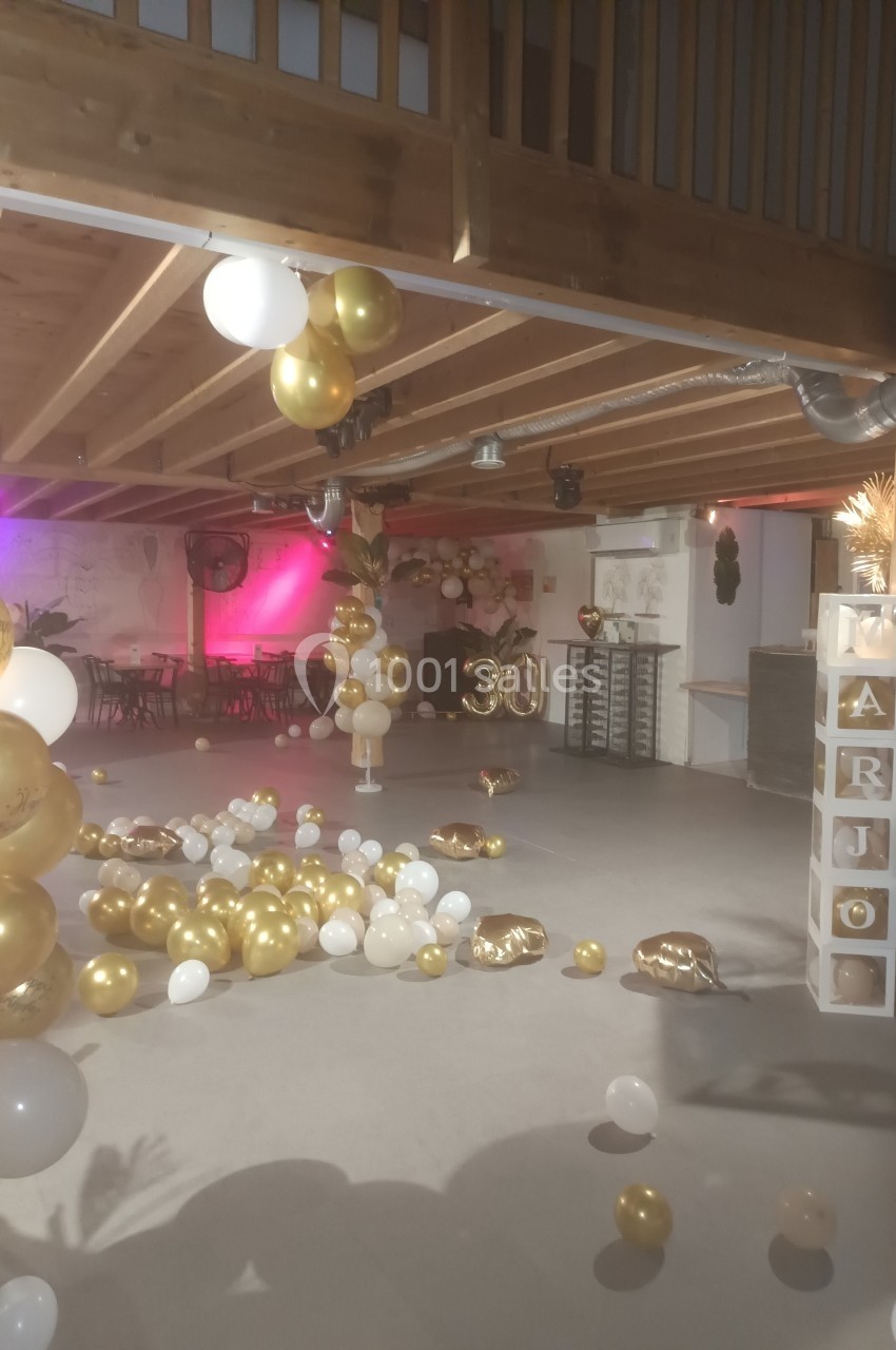 Salle décorée pour une fête avec ballons dorés et blancs, cubes décoratifs et chiffre 30 en ballon.