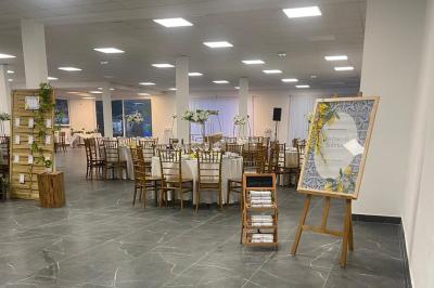 Salle de réception élégamment décorée avec des tables rondes, des chaises dorées et blanches, et des arrangements floraux.