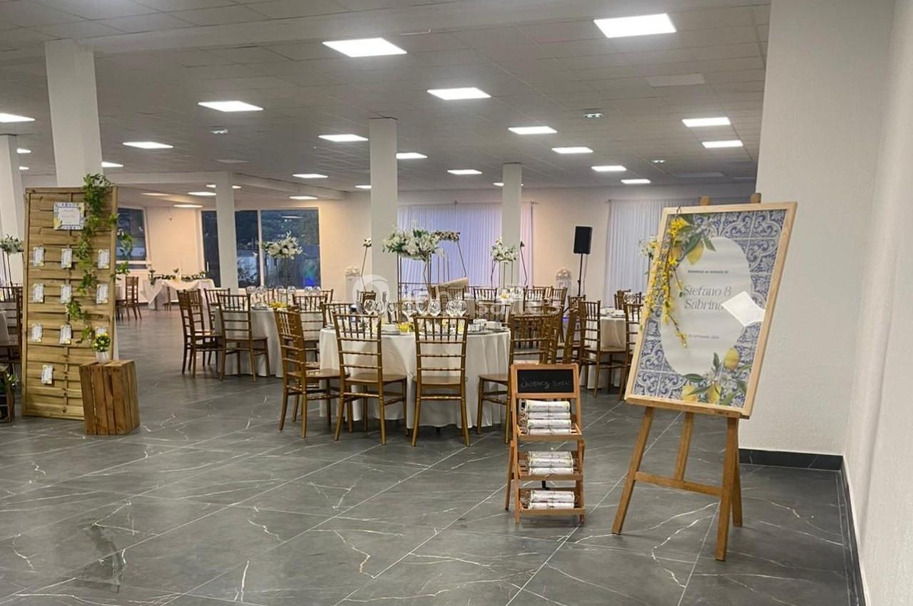 Salle de réception décorée avec des tables rondes, des chaises en bois et des arrangements floraux élégants.